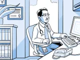 El médico de Nia, en su consultorio, trabajando en la computadora.